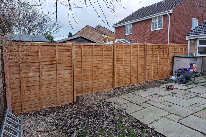 The same boundary with new fence panels and posts fitted and standing straight.