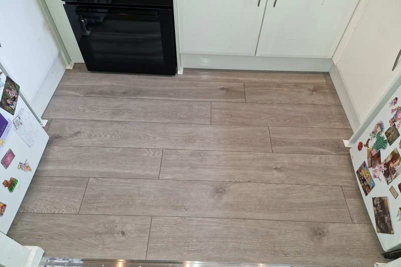 The same kitchen floor fitted with grey wood-effect flooring.
