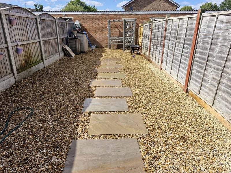 A low-maintenance garden laid to gravel with large sandstone stepping stones forming a path down its length.